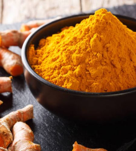 Organic turmeric powder in a bowl and fresh root close-up on the table. horizontal